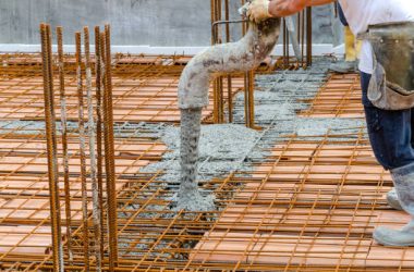 Construction worker pouring concrete into steel rebar frame
